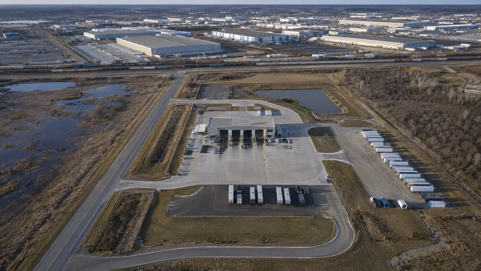An aerial view of a truck wash site showing its access road, truck parking, and the distribution warehouses nearby.